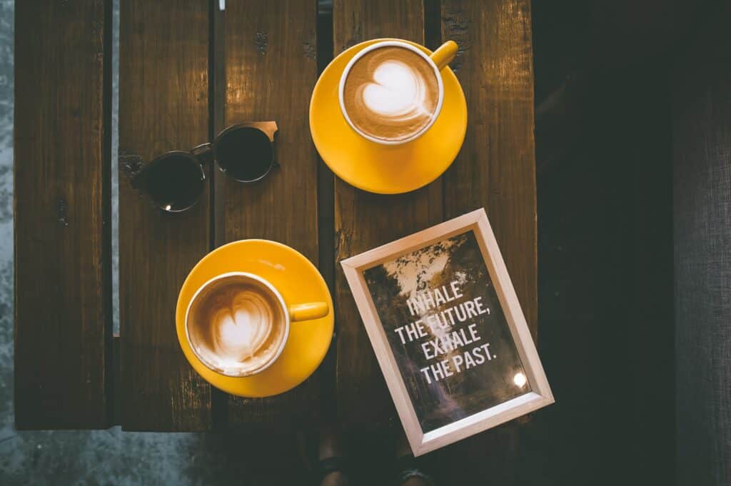 Two coffee cups with a framed text reminding the viewer to breathe: Inhale the future, and exhale the past.