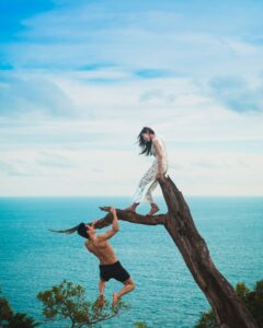 A couple playing on a log overlooking the ocean in Costa Rica.