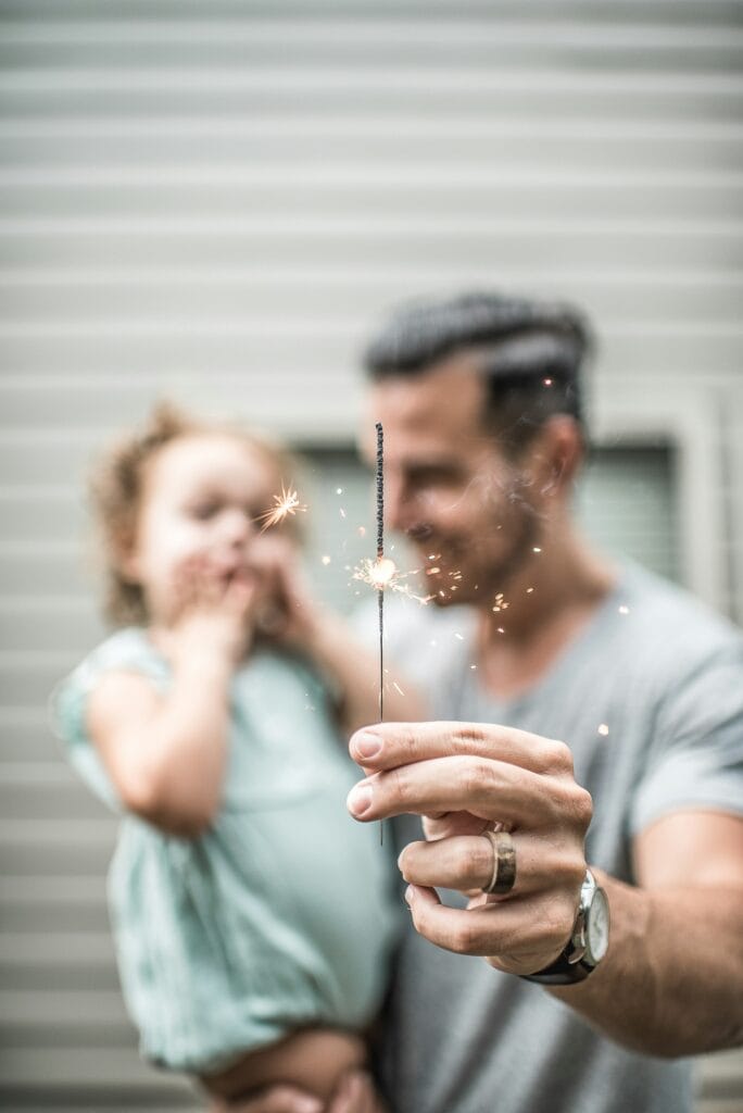 Dad holds daughter celebrating with a sparkler. Valentine's Day is a celebration of love.