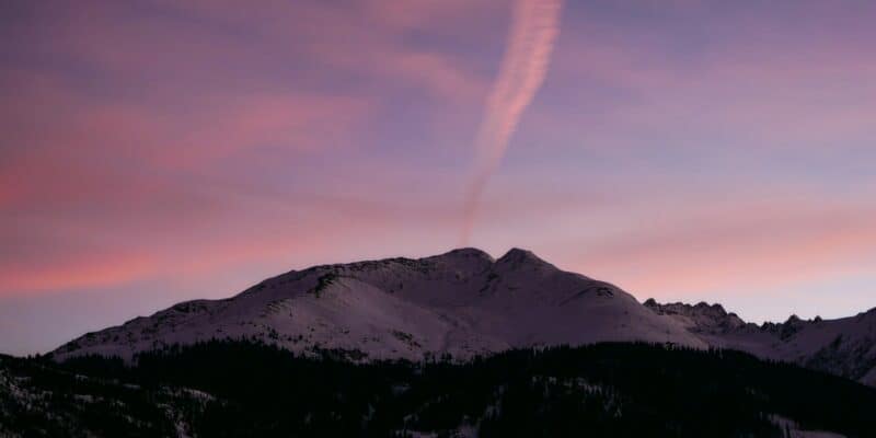 a purple sky with a contrail in the distance